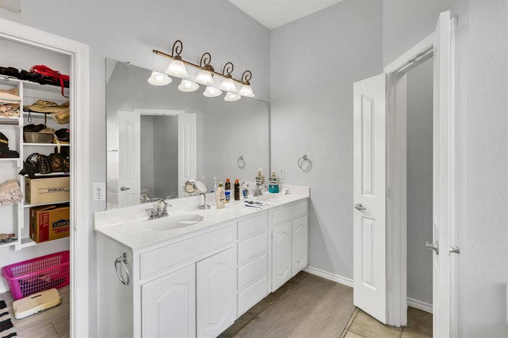 1506 Park Grove Drive, Irving, TX 75060 Dual-sink vanity with white cabinetry and integrated countertop, large vanity mirror, and overhead lighting fixture