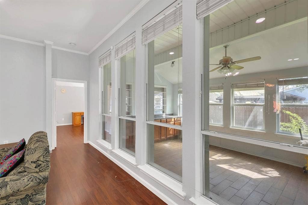 1506 Park Grove Drive, Irving, TX 75060 Wood-finish flooring throughout, featuring a series of tall windows, a sunroom with vaulted ceiling, ceiling fan, and tiled flooring