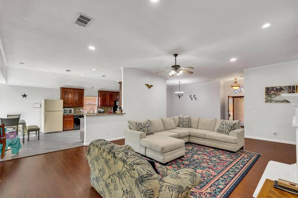 1506 Park Grove Drive, Irving, TX 75060 Hardwood flooring, recessed lighting, ceiling fan, crown molding, and a partial height wall opening to the kitchen