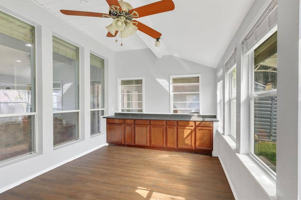 1506 Park Grove Drive, Irving, TX 75060 Vaulted ceiling with a ceiling fan, extensive windows, wood-finish flooring, and built-in cabinetry with a countertop