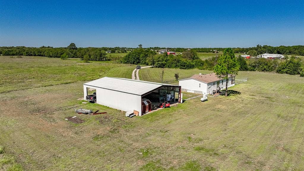 20132 County Road 818, Farmersville, TX 75442 Expansive grassy lot featuring a single-story residence and a large metal outbuilding with open bays