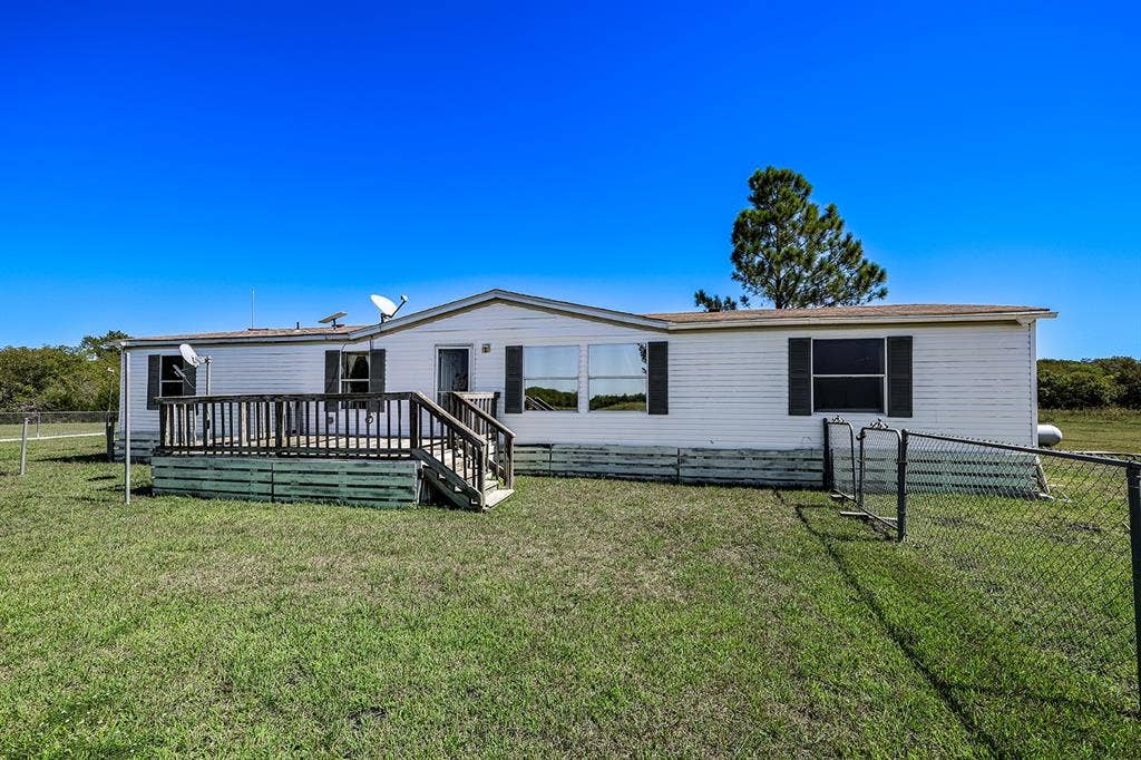 20132 County Road 818, Farmersville, TX 75442 White horizontal siding exterior with dark shutters, front wooden deck, and a chain-link fence