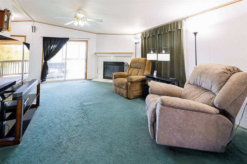 20132 County Road 818, Farmersville, TX 75442 Fireplace with white mantel, ceiling fan, sliding glass door, and green carpeting