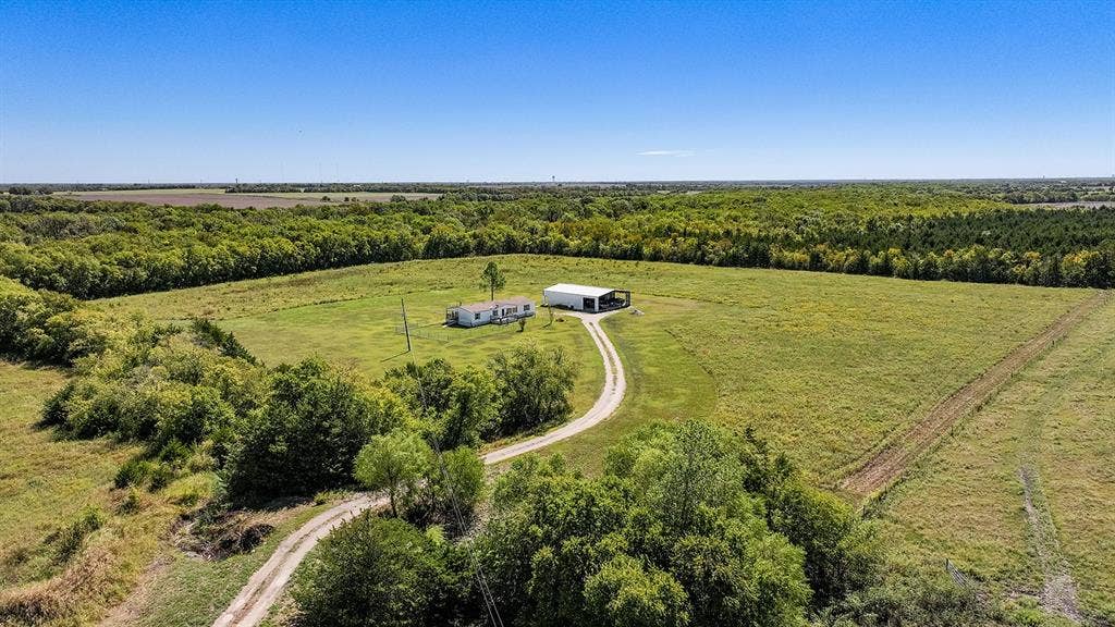 20132 County Road 818, Farmersville, TX 75442 Expansive acreage featuring a single-story residence, a large outbuilding, and a winding driveway