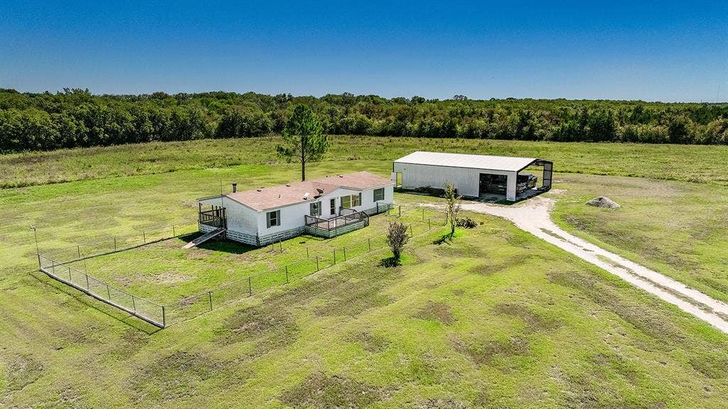 20132 County Road 818, Farmersville, TX 75442 Expansive green acreage with a single-story residence, detached covered structure, and a dedicated driveway