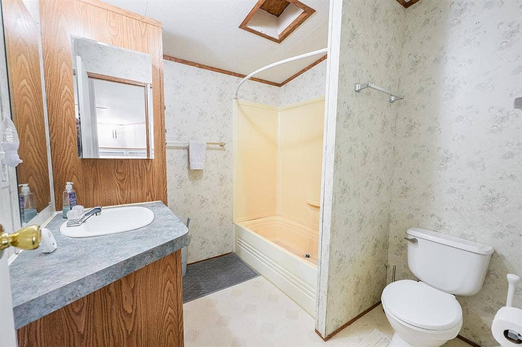 20132 County Road 818, Farmersville, TX 75442 Bathroom featuring a wood-finish vanity with a gray countertop, a built-in tub/shower combination, and a white toilet