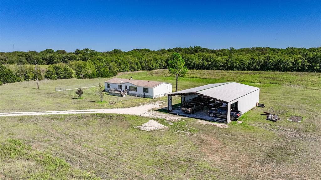 20132 County Road 818, Farmersville, TX 75442 Spacious lot featuring a single-story residence with a covered porch and an expansive detached metal outbuilding