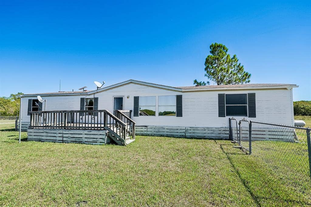 20132 County Road 818, Farmersville, TX 75442 Exterior featuring white siding, a built-in wooden deck with railings, dark window shutters, and a chain-link fence