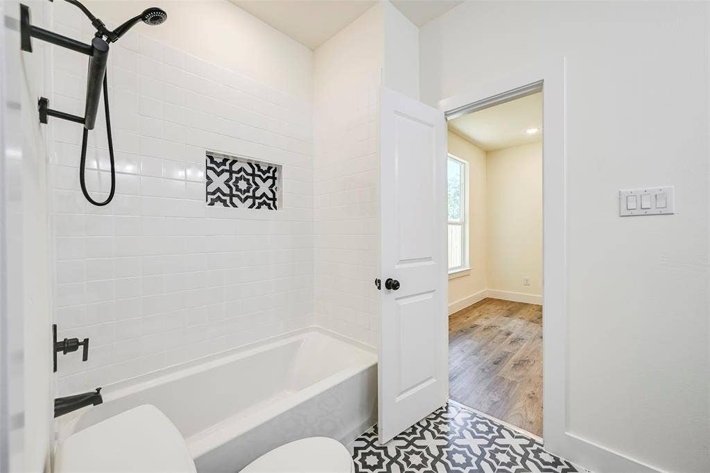 4418 Myrtle, Dallas, TX 75215 Bathroom featuring a white subway tile surround, patterned tile flooring, and matte black fixtures