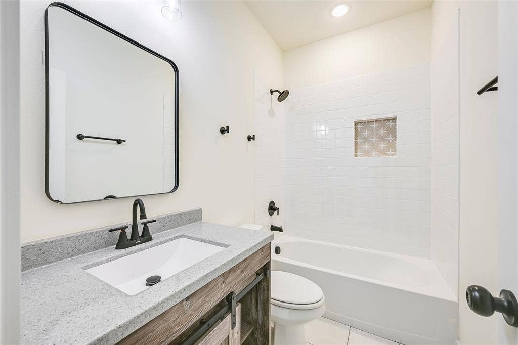 4418 Myrtle, Dallas, TX 75215 Bathroom featuring a white subway tile shower surround with a decorative niche, a white tub, and matte black fixtures