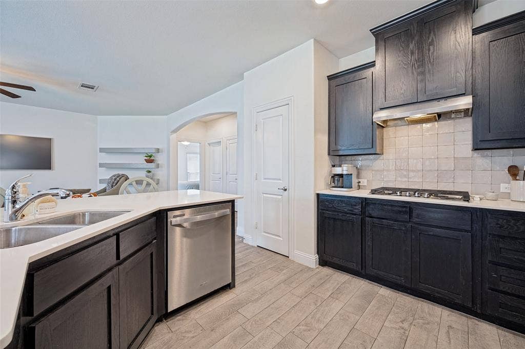 1429 Green Valley Way, Celina, TX 75009 Kitchen featuring dark wood-finish cabinetry, stainless steel appliances, light countertops, and a subway tile backsplash