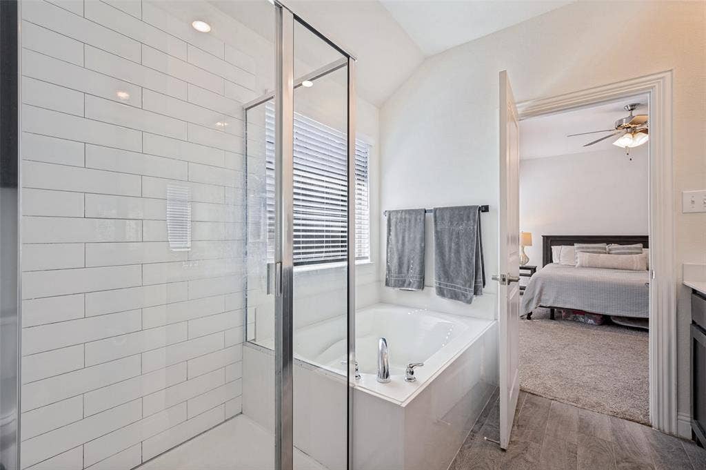 1429 Green Valley Way, Celina, TX 75009 Glass-enclosed shower with subway tile surround, separate soaking tub with chrome fixtures, and wood-finish flooring