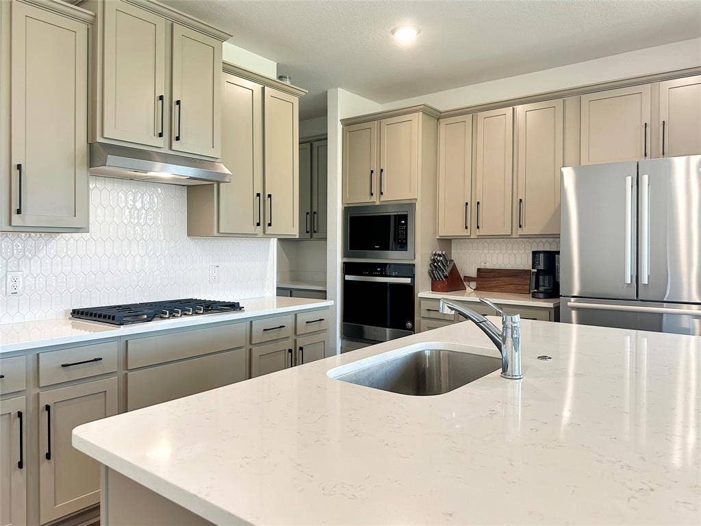 2117 Proteus Drive, Haslet, TX 76052 Kitchen with appliances with stainless steel finishes, light stone counters, backsplash, and sink