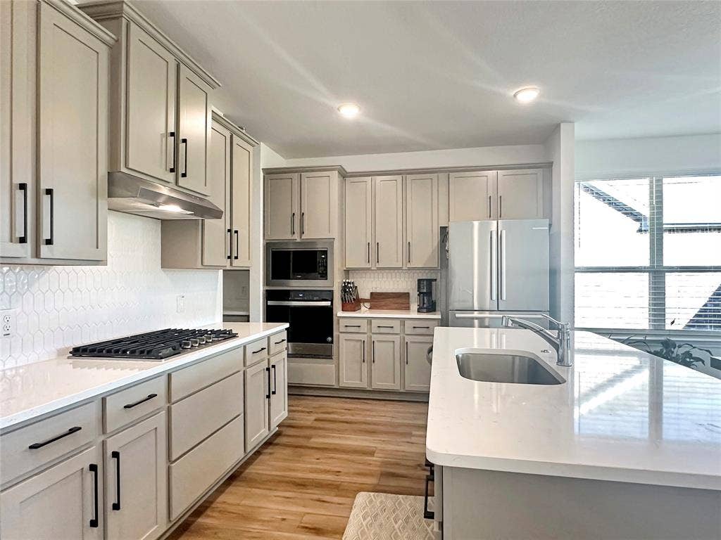 2117 Proteus Drive, Haslet, TX 76052 Kitchen with light hardwood / wood-style flooring, appliances with stainless steel finishes, gray cabinetry, and sink