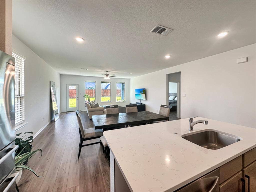 2117 Proteus Drive, Haslet, TX 76052 Kitchen featuring light stone countertops, dark hardwood / wood-style flooring, a center island with sink, sink, and ceiling fan