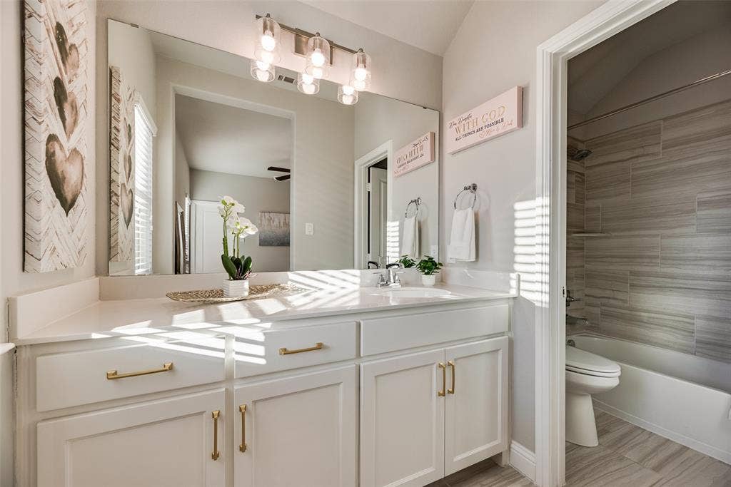 White shaker-style cabinetry with gold-tone hardware, a single undermount sink, and a white countertop