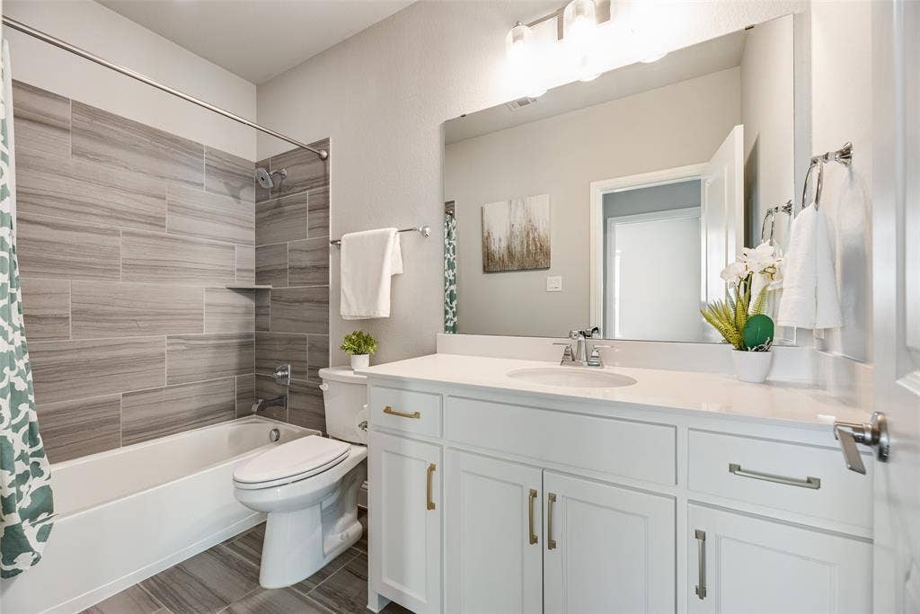 Full bathroom featuring a white vanity with a single sink, light-colored countertop, and a built-in bathtub with a tile surround and shower fixture