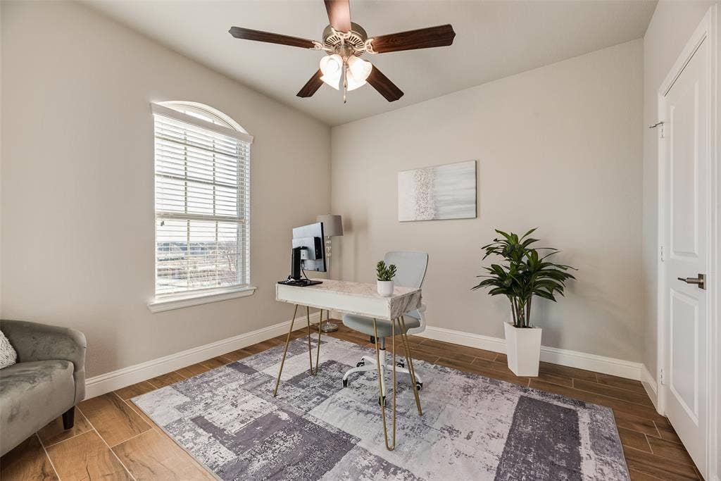 Wood-finish flooring, arched window with horizontal blinds, overhead ceiling fan with lighting, and a paneled interior door