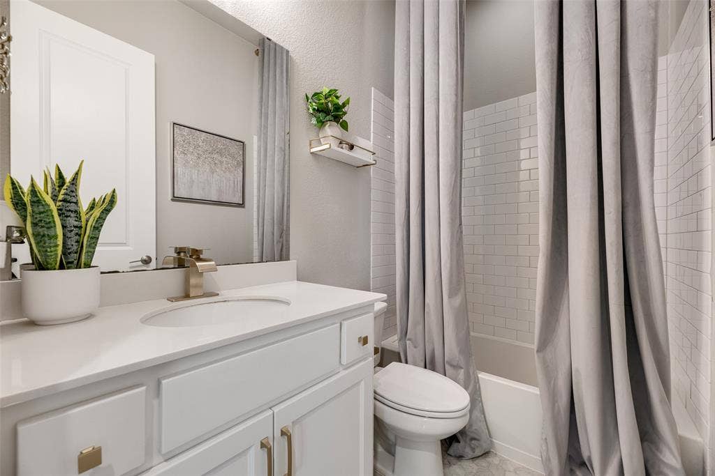 White vanity with gold-finish hardware, undermount sink, and a single-handle faucet