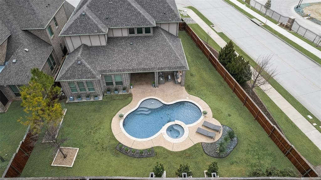 Custom-shaped swimming pool with an integrated spa, surrounded by a concrete patio