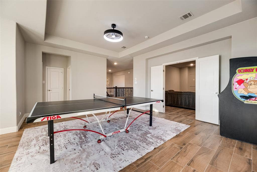 Wood-finish flooring throughout, tray ceiling, and modern semi-flushmount lighting