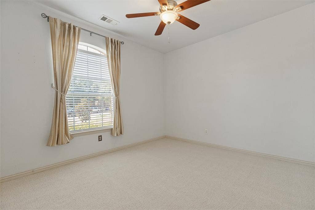 10796 Astoria Drive, Frisco, TX 75035 Spacious secondary bedroom featuring brand-new carpet, a ceiling fan, and a large arched window that brings in abundant natural light.