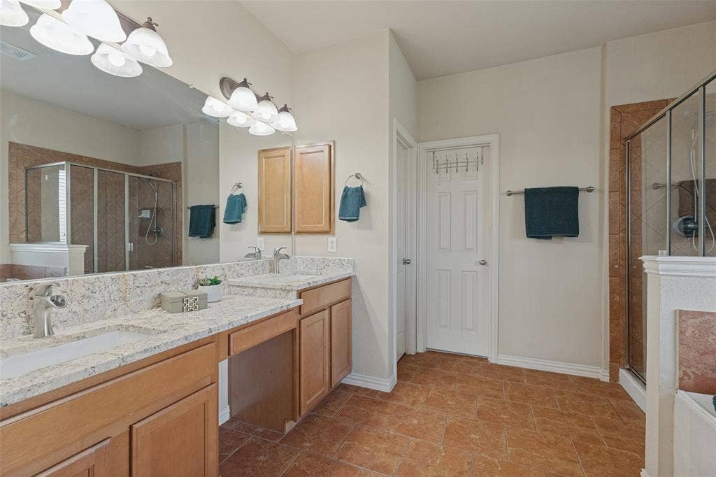 10796 Astoria Drive, Frisco, TX 75035 Spacious primary bath features dual vanities with granite countertops, abundant storage, and a large mirror, offering plenty of space for everyday routines.