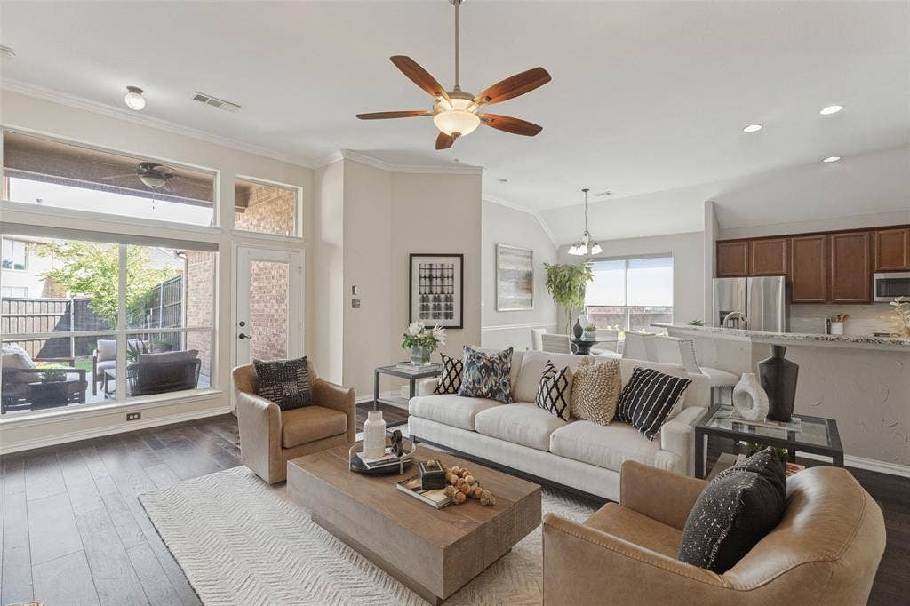10796 Astoria Drive, Frisco, TX 75035 Spacious living area with soaring ceilings and rich hardwood floors flows seamlessly into the kitchen and breakfast nook, while oversized windows fill the room with natural light and overlook the covered patio.