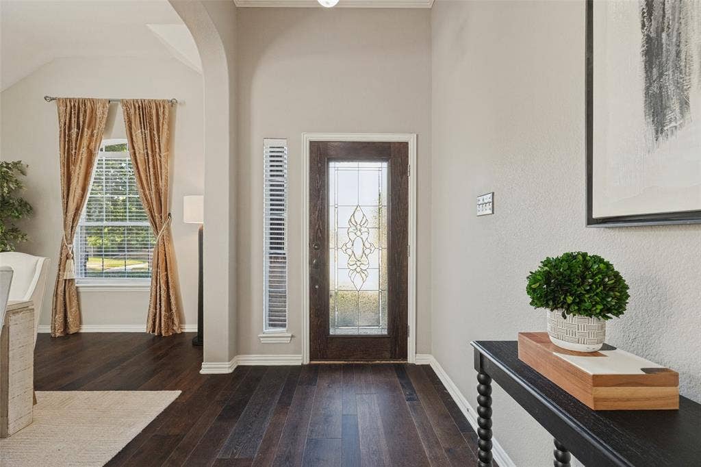 10796 Astoria Drive, Frisco, TX 75035 A warm and welcoming entry featuring rich hardwood floors, soaring ceilings, and a beautiful decorative glass front door that fills the space with natural light..