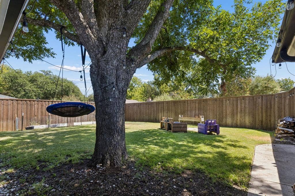 2408 Grandview Drive, Plano, TX 75075 Spacious backyard featuring a substantial mature tree, a manicured lawn area, and a privacy fence