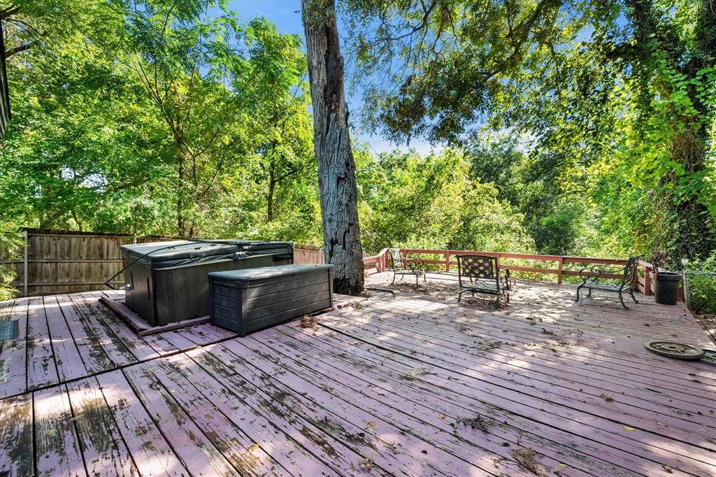 656 The Meadows Parkway, DeSoto, TX 75115 Expansive wood deck with a built-in hot tub, surrounded by mature trees, and featuring a wood privacy fence