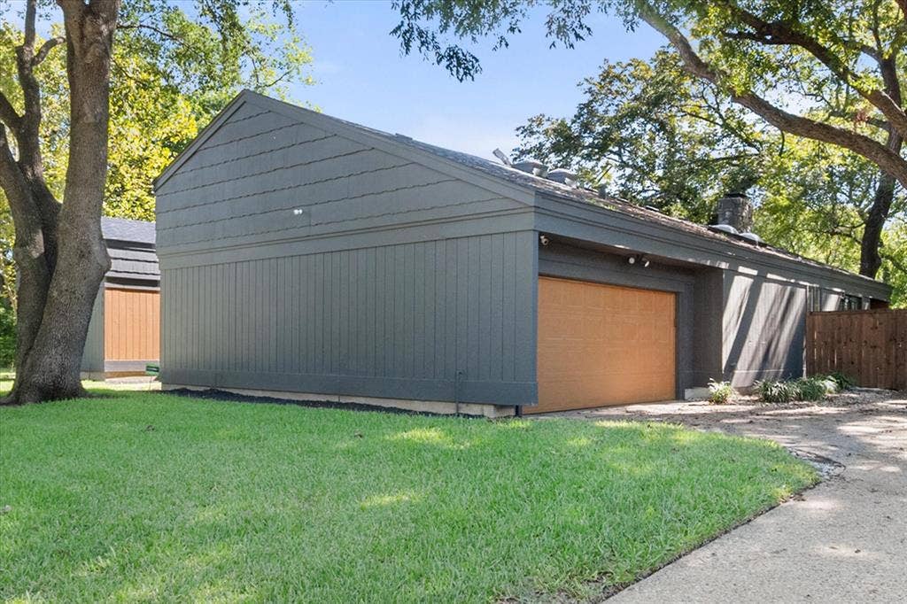 656 The Meadows Parkway, DeSoto, TX 75115 Horizontal siding with vertical paneling accents, light-toned wood-finish garage door, and a partially visible wood privacy fence