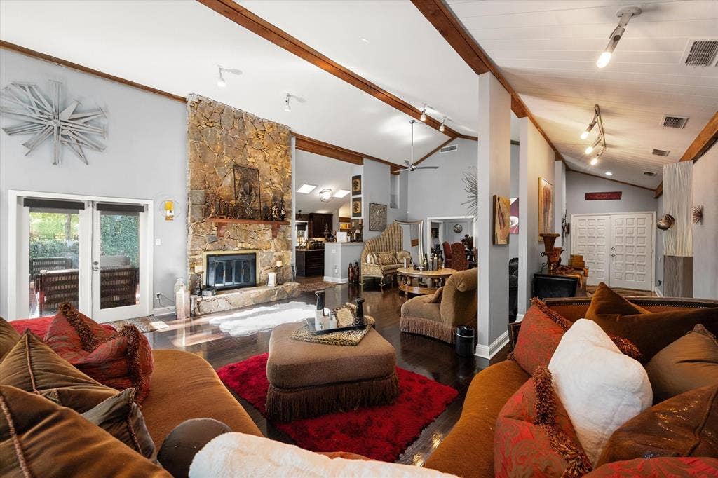 656 The Meadows Parkway, DeSoto, TX 75115 Vaulted ceilings with exposed wood beams, stone fireplace, dark wood-finish flooring, and double patio doors