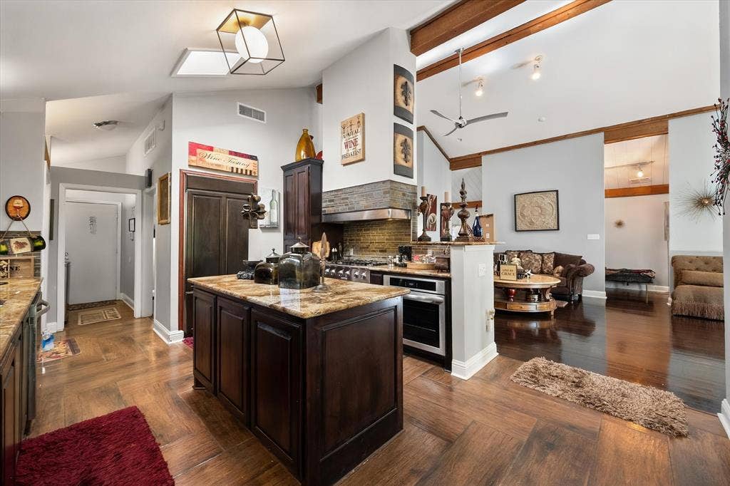 656 The Meadows Parkway, DeSoto, TX 75115 Kitchen featuring a central island, wood-finish flooring, vaulted ceiling with exposed beams, and stainless steel appliances