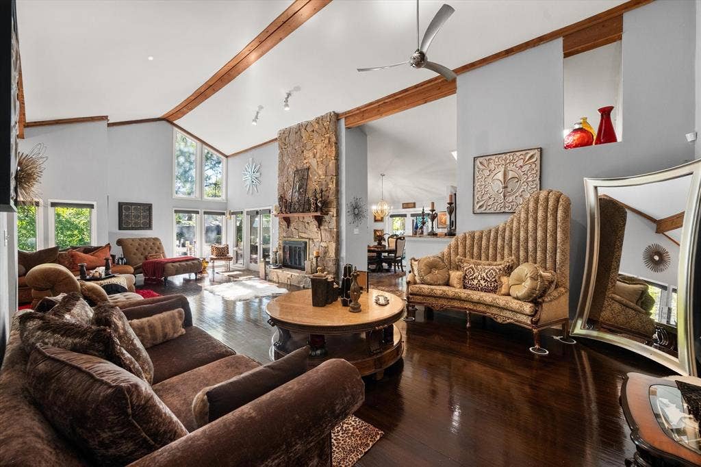 656 The Meadows Parkway, DeSoto, TX 75115 Vaulted ceilings with exposed wood beams, a stone-clad fireplace, large windows, and dark wood-finish flooring
