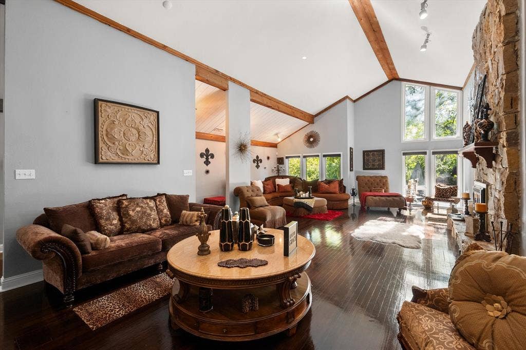 656 The Meadows Parkway, DeSoto, TX 75115 Vaulted ceilings with exposed wood beams, expansive windows, dark wood-finish flooring, and a stone-clad fireplace