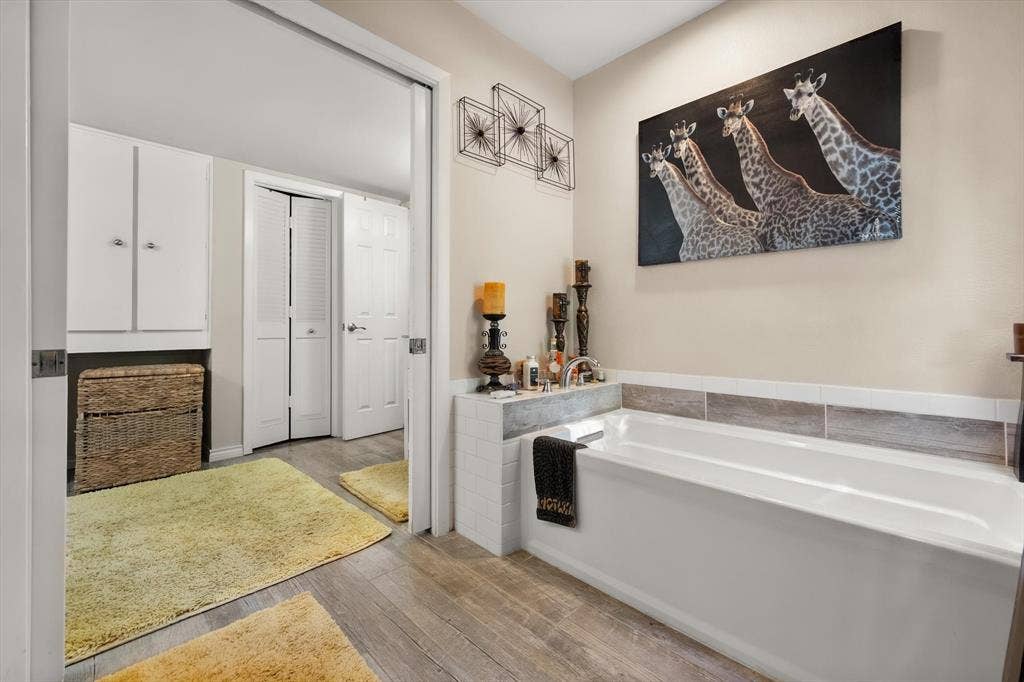 656 The Meadows Parkway, DeSoto, TX 75115 Built-in tub with tile surround, wood-finish flooring, and white storage cabinetry