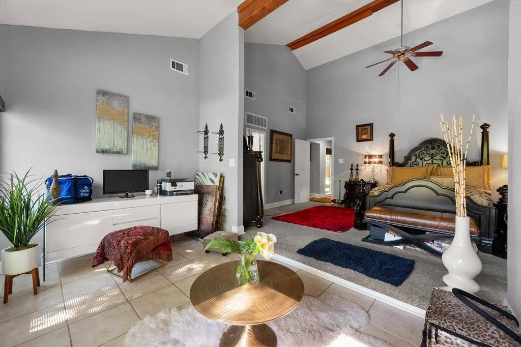 656 The Meadows Parkway, DeSoto, TX 75115 Vaulted ceiling with exposed wood beams, ceiling fan, tile flooring, and a raised carpeted area