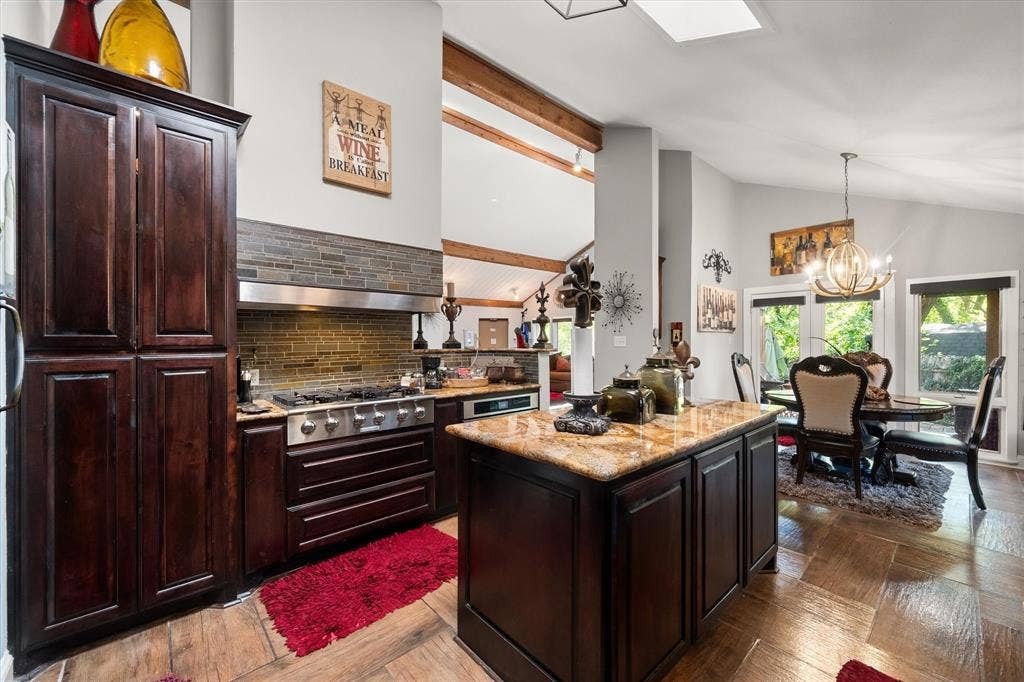 656 The Meadows Parkway, DeSoto, TX 75115 Kitchen featuring a large central island with a stone countertop, dark wood-finish cabinetry, stainless steel range with a ventilation hood, and wood-finish flooring
