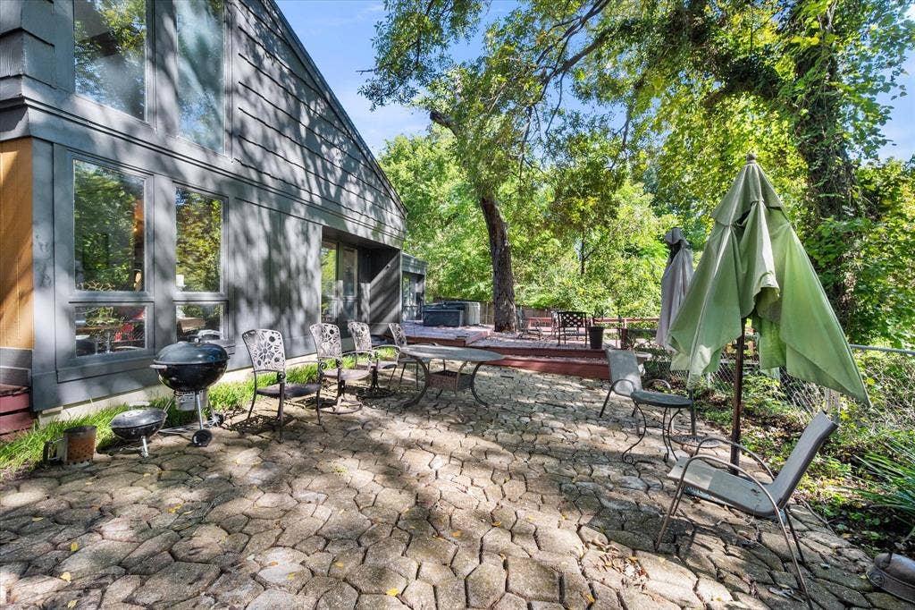 656 The Meadows Parkway, DeSoto, TX 75115 Exterior featuring large windows, gray siding, a stone paver patio, and a raised wood deck