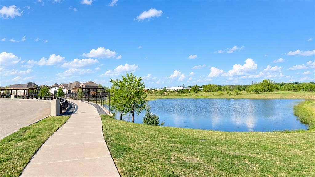 1613 Sandhill Lane, Celina, TX 75009 Waterfront setting featuring a paved pathway, manicured lawn, and lush landscaping