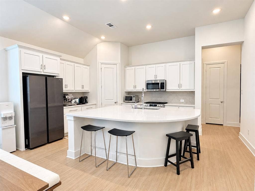 1613 Sandhill Lane, Celina, TX 75009 White shaker cabinetry with brushed nickel hardware, stainless steel appliances, solid surface countertops, and light wood-finish flooring