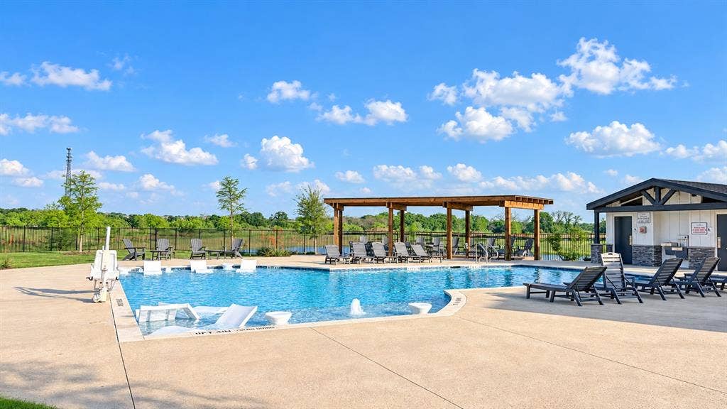 1613 Sandhill Lane, Celina, TX 75009 Swimming pool with concrete decking, a wooden pergola, and an adjacent structure with a stone facade