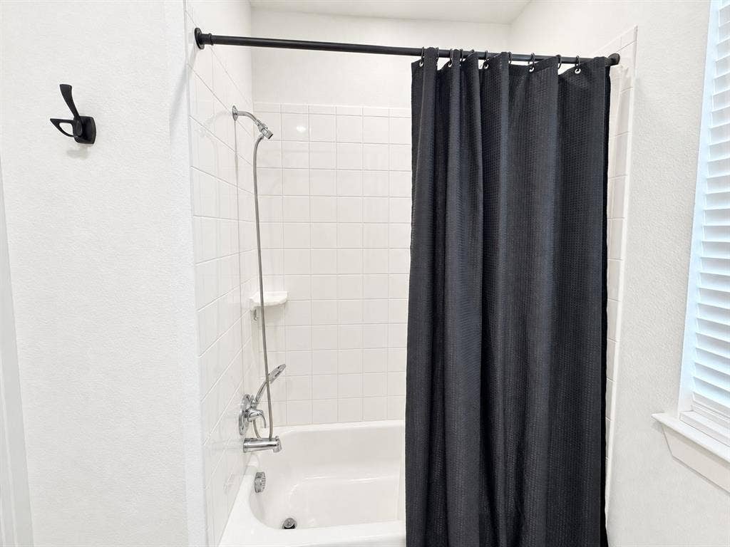 1613 Sandhill Lane, Celina, TX 75009 Bathtub with white tile surround, chrome fixtures, and a matte black shower rod