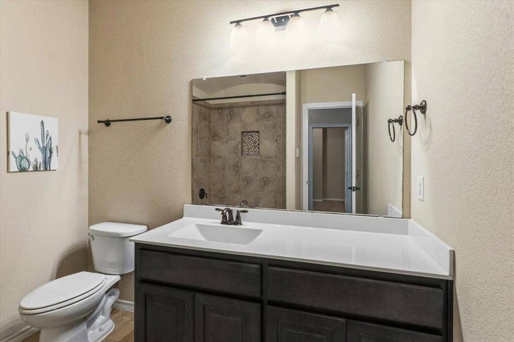 1713 Falling Star Drive, Fort Worth, TX 76052 Dark wood-finish vanity with white countertop, integrated sink, and bronze-finish faucet