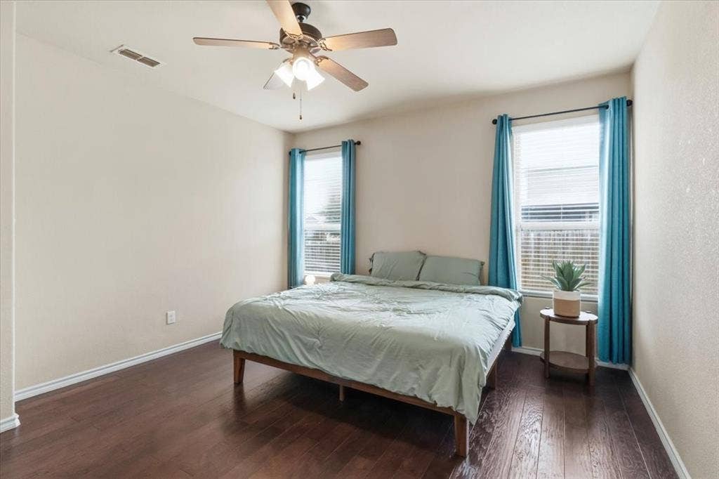 1713 Falling Star Drive, Fort Worth, TX 76052 Wood-finish flooring throughout, two windows with blinds, and a ceiling fan with integrated lighting