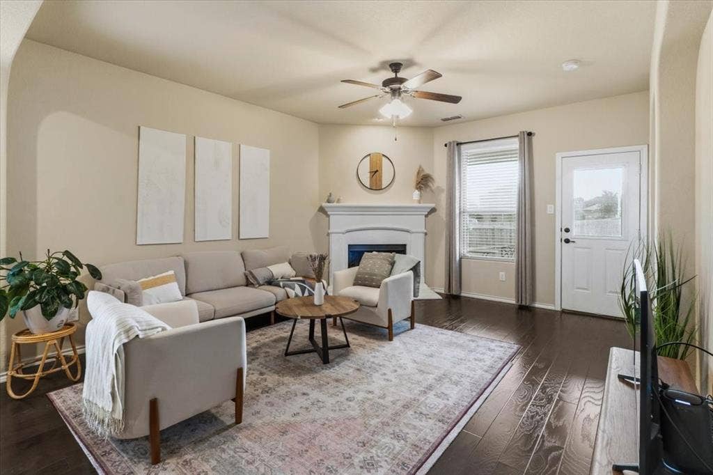 1713 Falling Star Drive, Fort Worth, TX 76052 Living area featuring dark wood-finish flooring, a built-in fireplace with a mantel, and a ceiling fan with integrated lighting