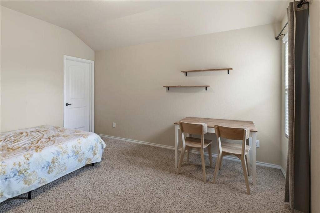 1713 Falling Star Drive, Fort Worth, TX 76052 Neutral-toned walls, vaulted ceiling, white interior door with black hardware, carpeted flooring, and window with blinds