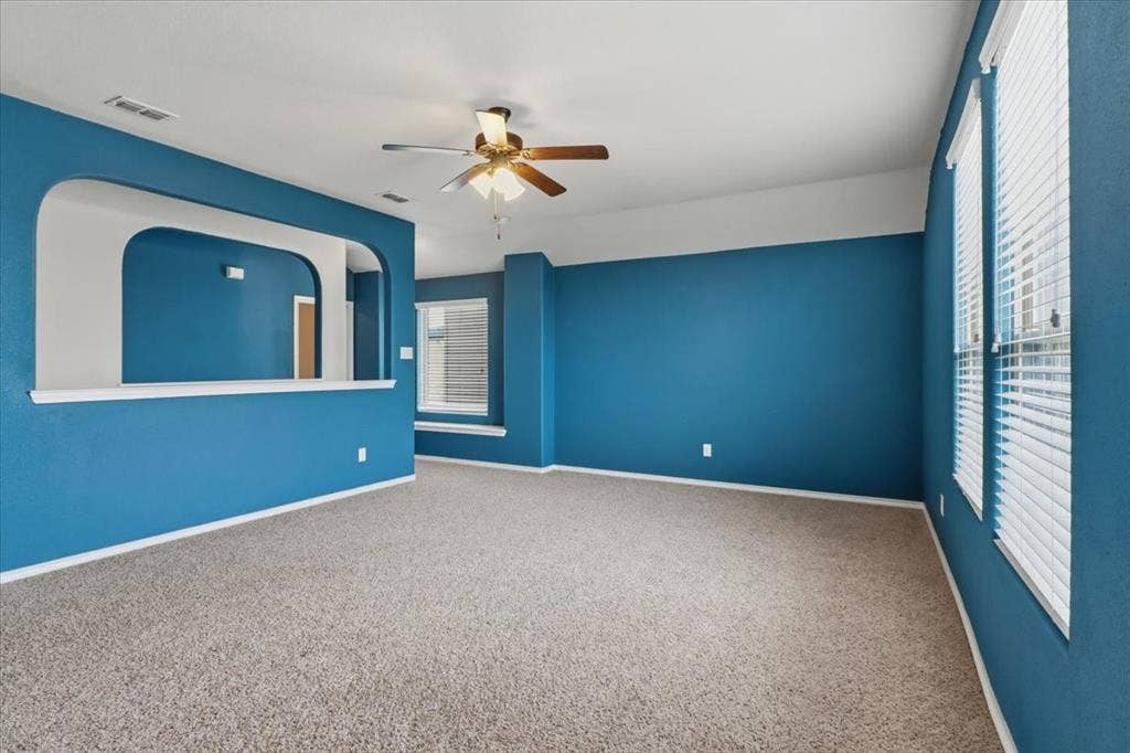 1713 Falling Star Drive, Fort Worth, TX 76052 Carpeted interior space featuring a ceiling fan, multiple windows with blinds, and a built-in architectural archway