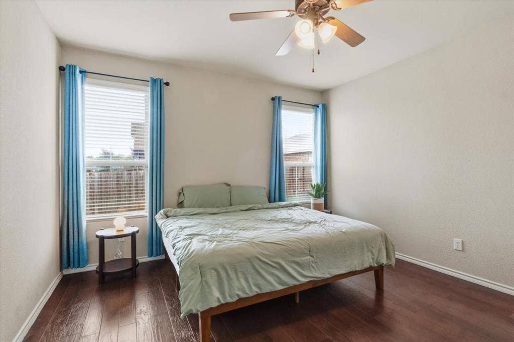 1713 Falling Star Drive, Fort Worth, TX 76052 Wood-finish flooring, two window openings with blinds, and a ceiling fan with integrated lighting